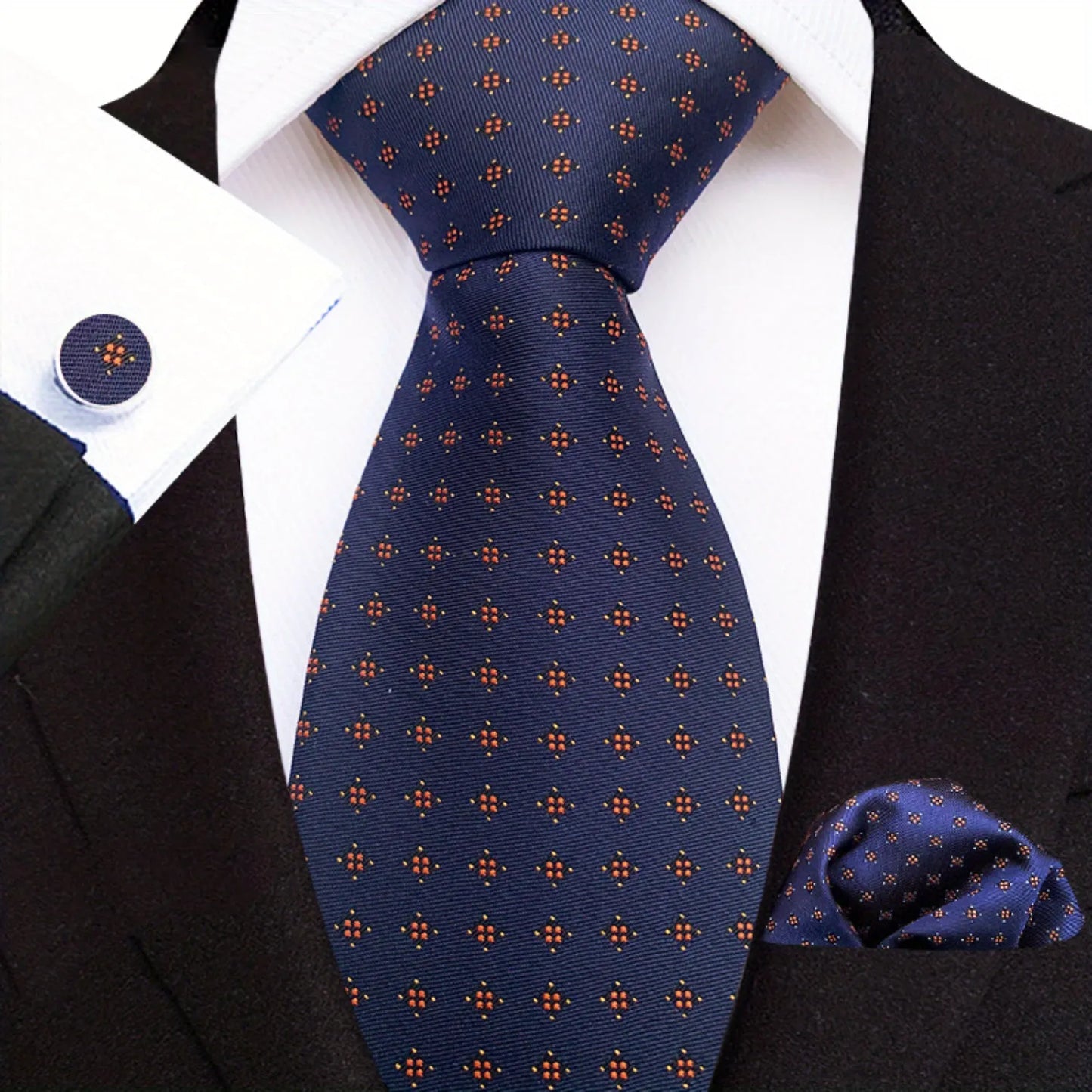A set including a blue necktie with a geometric pattern, a matching pocket square, and a pair of cufflinks, displayed on a mannequin wearing a black suit and a white shirt.