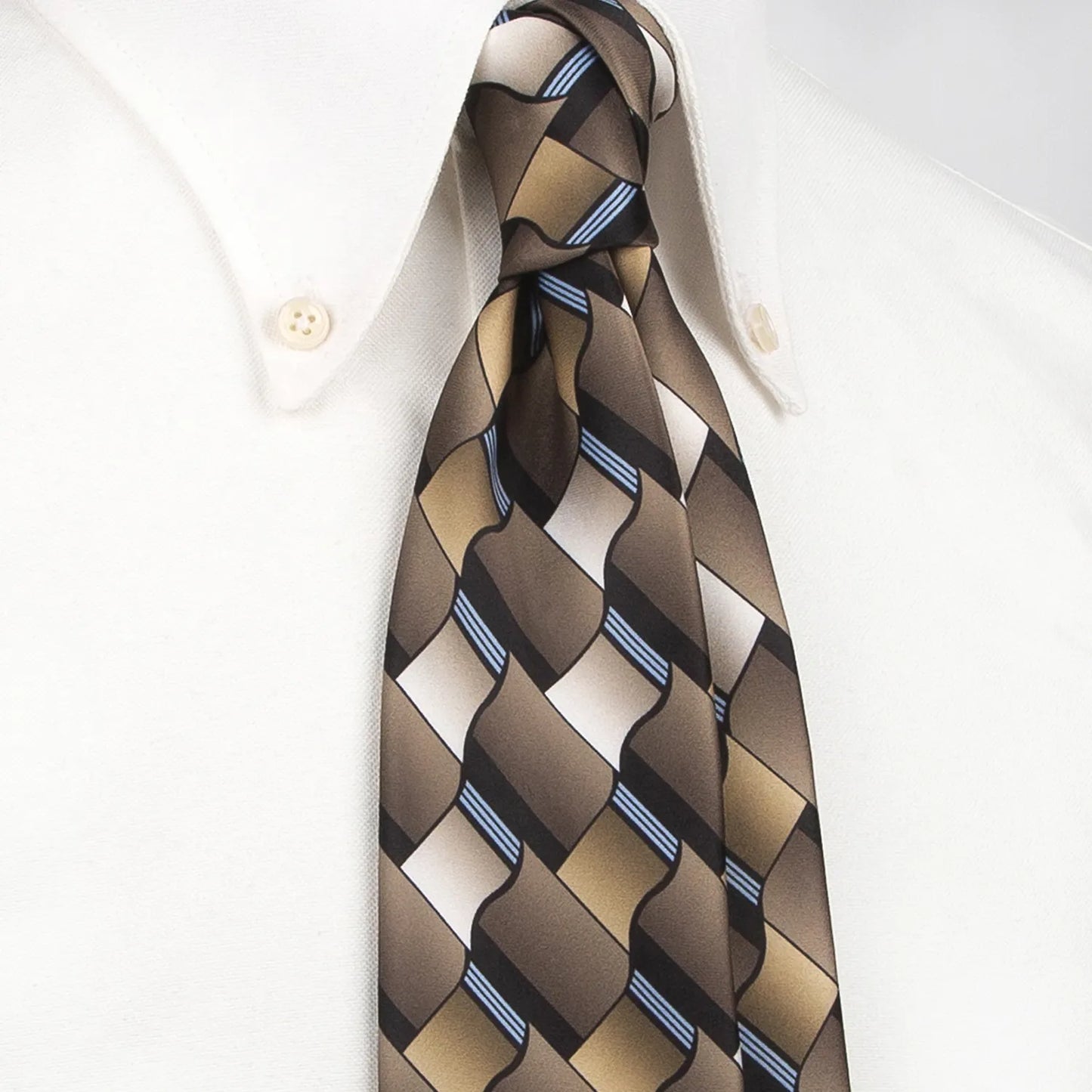 A close-up shows a men's necktie with a contemporary geometric pattern in various shades of brown, black, and thin blue stripes tied in a four-in-hand knot on a crisp white button-down shirt, suitable for business and stylish events.