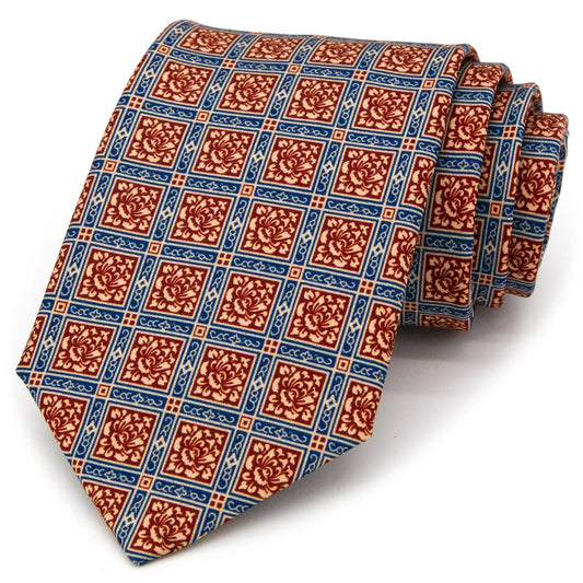 A red-brown, blue, and beige men's necktie featuring a complex geometric pattern with floral motifs is casually knotted against a white background.
