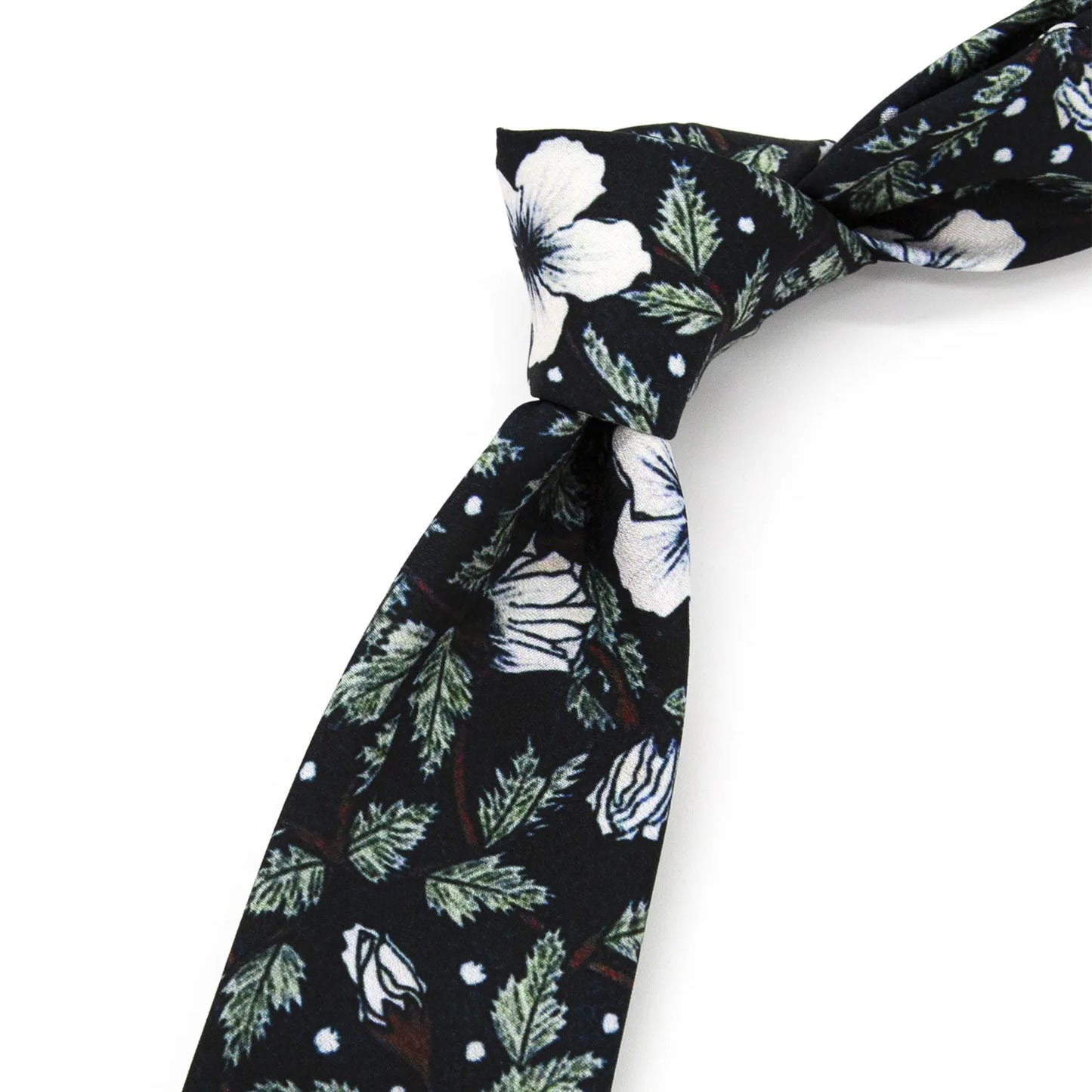 A neatly rolled deep black men's necktie displaying its minimalist floral pattern with white blossoms, green leaves, and white dot accents against a clean white surface.