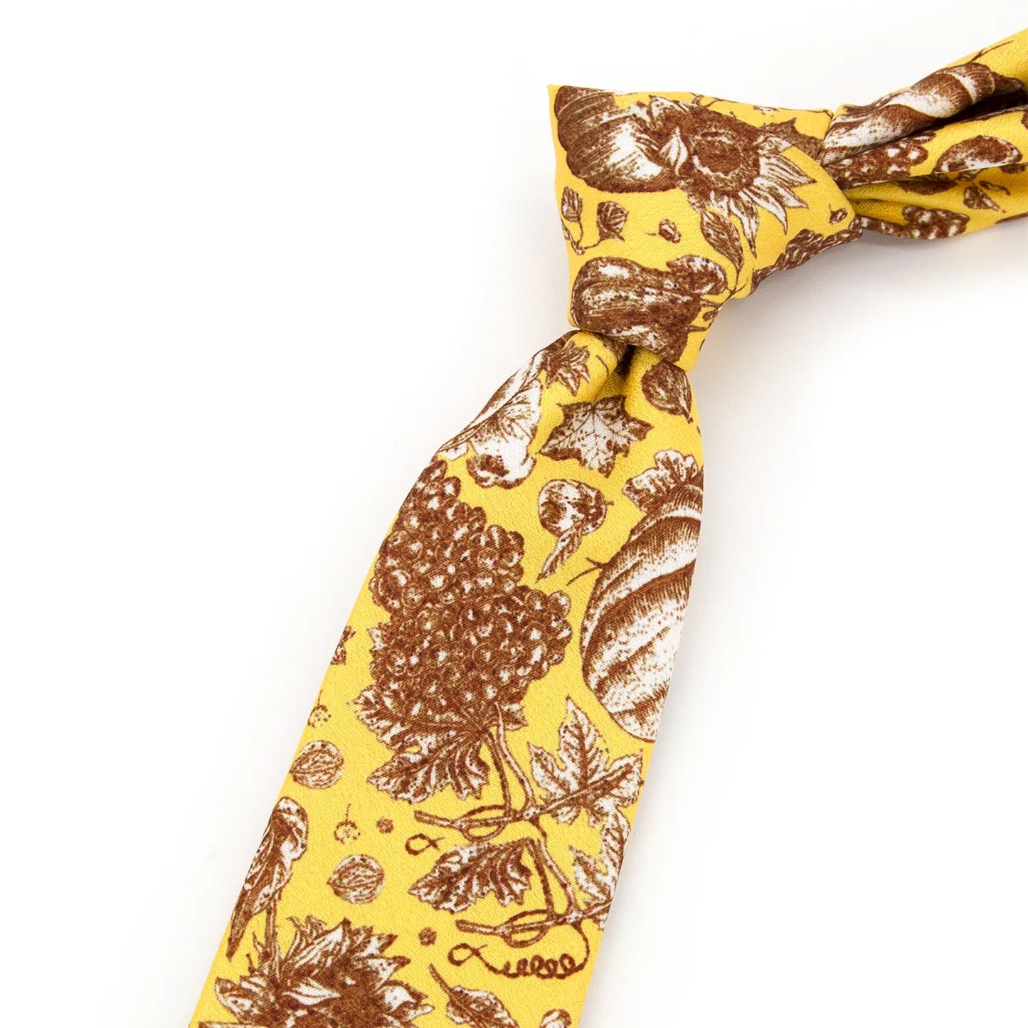 A neatly rolled bright yellow men's necktie displaying its festive autumn harvest pattern with pumpkins, grapes, and sunflowers in brown and beige against a clean white surface.