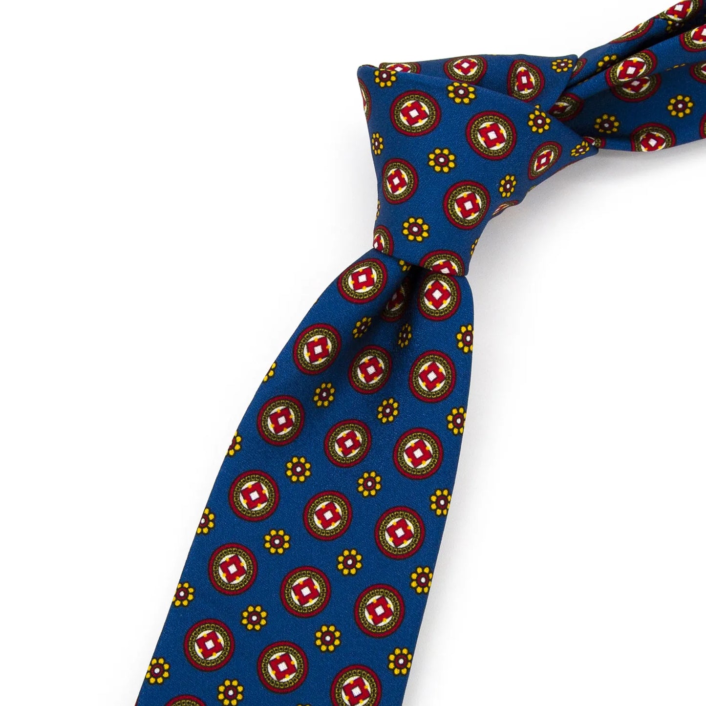 A neatly rolled bright blue men's necktie displaying its vibrant geometric medallion pattern in red and white, surrounded by small yellow floral dots, against a clean white surface.