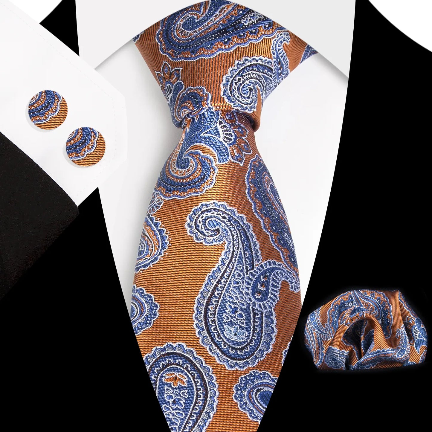 A coordinated set featuring a rolled rust orange and blue paisley polyester tie, a folded matching pocket square, and two round cufflinks, all displaying an intricate pattern on a white background.