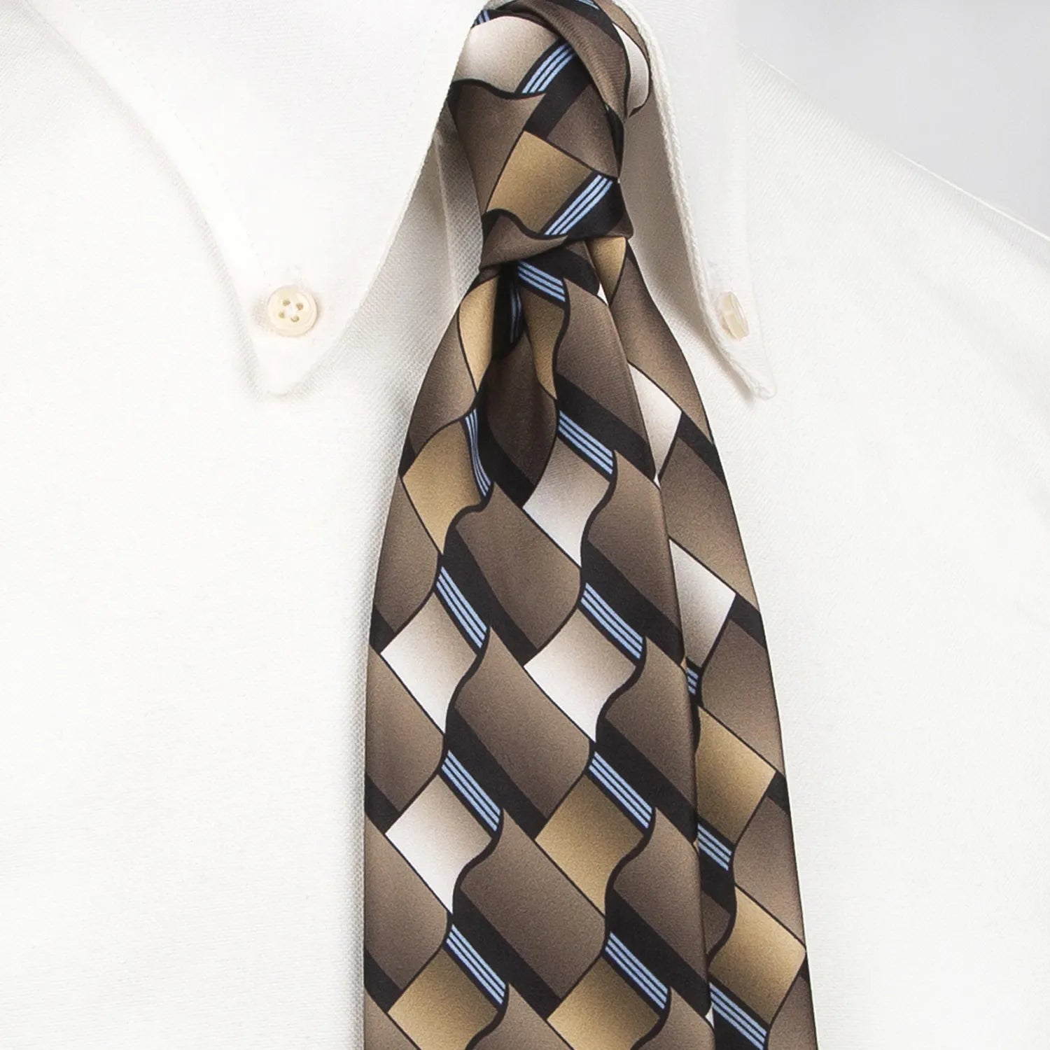 A close-up shows a men's necktie with a contemporary geometric pattern in various shades of brown, black, and thin blue stripes tied in a four-in-hand knot on a crisp white button-down shirt, suitable for business and stylish events.
