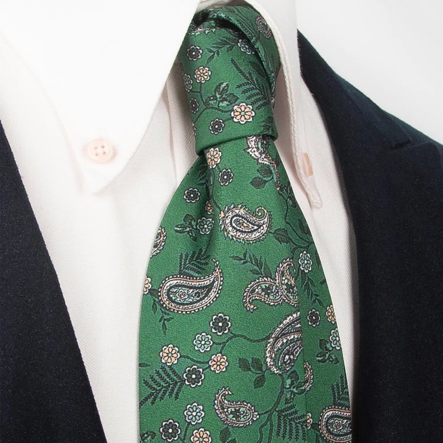 A dark blue men's necktie featuring an intricate repeating geometric pattern in lighter blue and white is casually knotted against a plain white background.