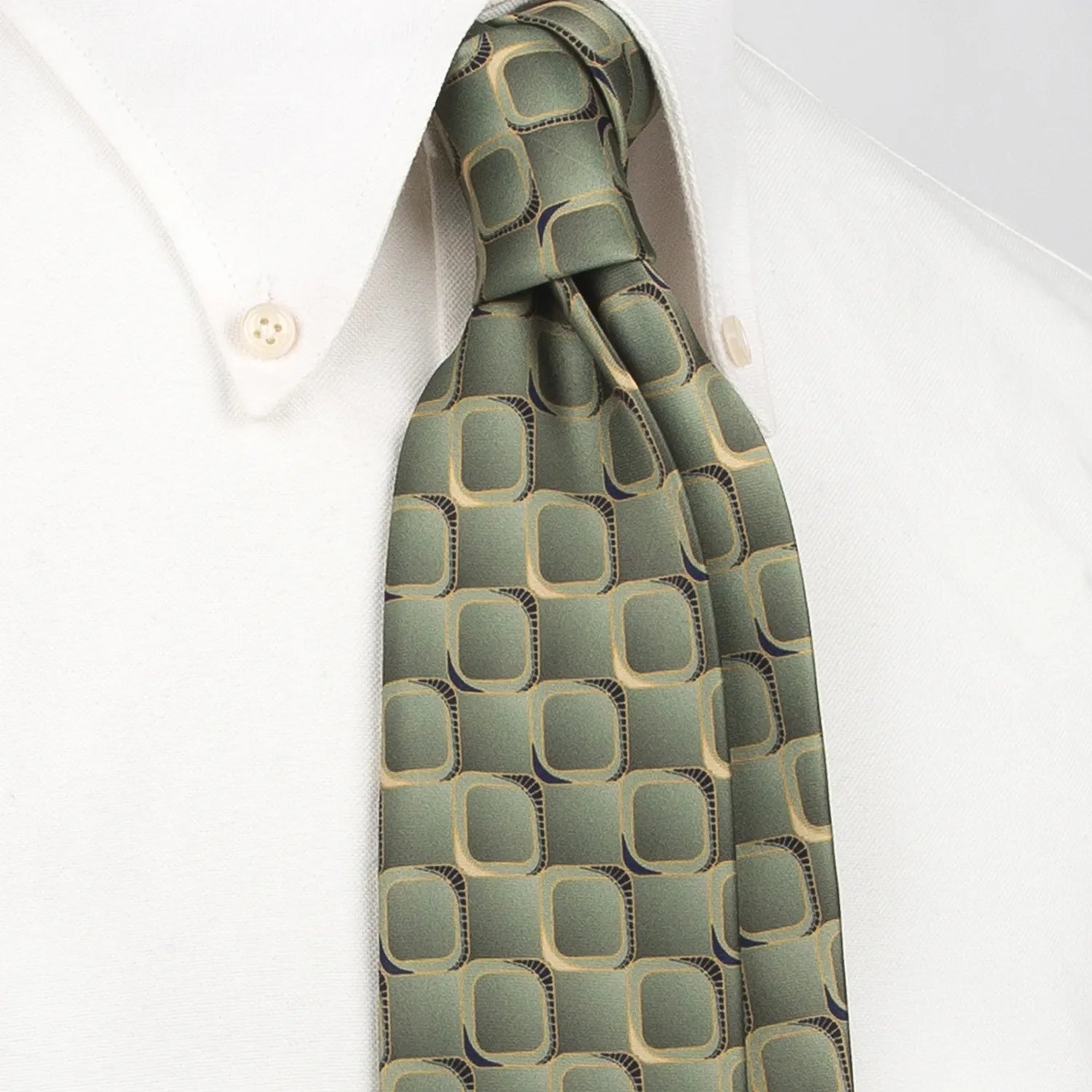 A gray-green men's necktie featuring a modern rounded square pattern with brown and black borders and gold accents is tied in a four-in-hand knot on a crisp white button-down shirt, suitable for business and professional settings.
