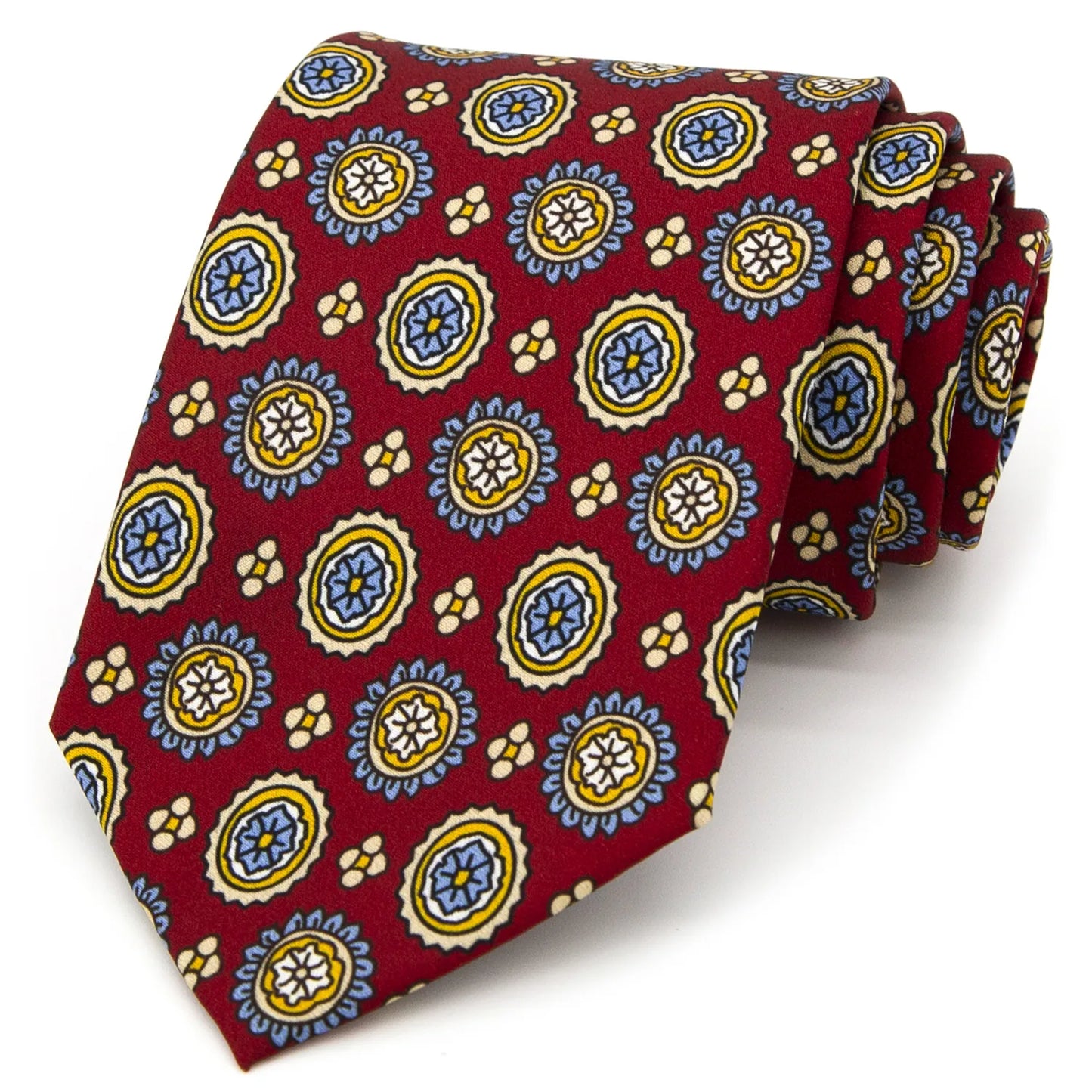 A deep red men's necktie featuring a repeating pattern of vibrant circular floral designs in blue, yellow, and white, with small beige accents, is casually knotted against a white backdrop.