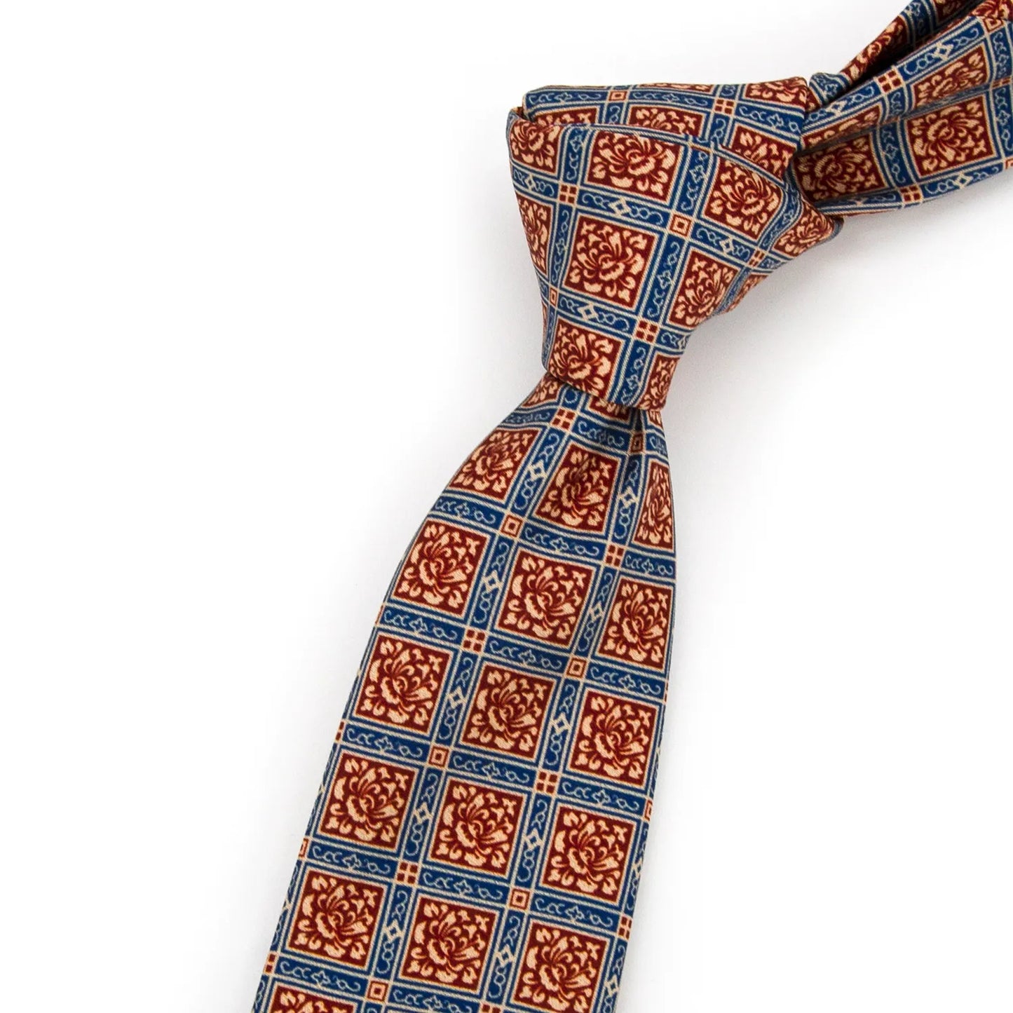 An elegant red-brown, blue, and beige men's necktie from XueDouLing Tie with an intricate geometric floral design is tied in a four-in-hand knot on a crisp white button-down shirt under a dark blazer, suitable for business and elegant events.