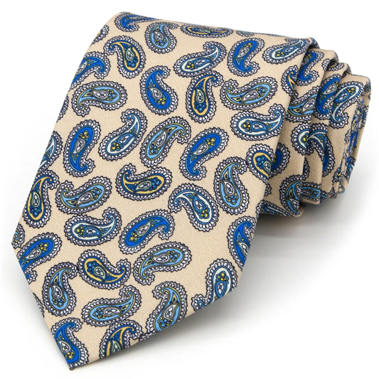 A beige men's necktie featuring a classic paisley pattern in shades of blue and yellow is casually knotted against a white background.
