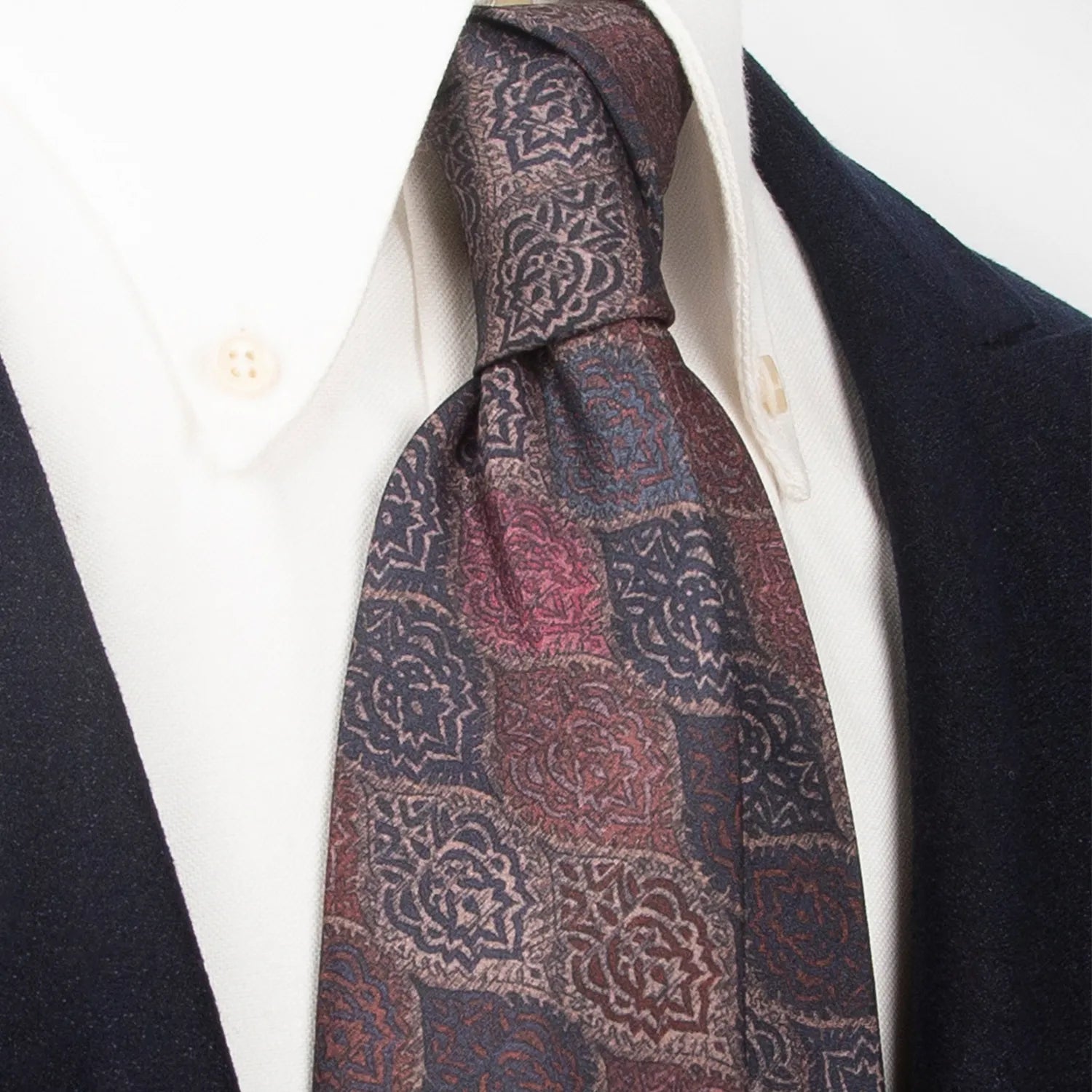 A refined dark brown men's necktie from XueDouLing Tie showcasing its intricate retro motif design in red-brown, dark blue, and beige, tied in a four-in-hand knot on a crisp white button-down shirt under a dark blazer, suitable for business and sophisticated events.