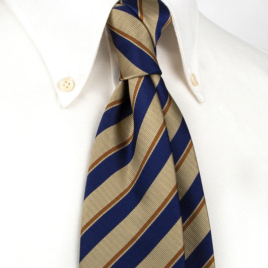 A men's necktie featuring diagonal stripes in navy blue, beige, and brown is tied in a four-in-hand knot on a crisp white button-down shirt, suitable for business and professional attire.