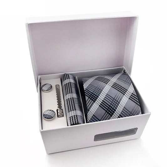 A complete men's tie set laid out, featuring a deep navy blue necktie with classic diagonal stripes in tan and beige, a matching pocket square, and a pair of sleek silver-toned cufflinks, suggesting sophisticated business or formal attire.