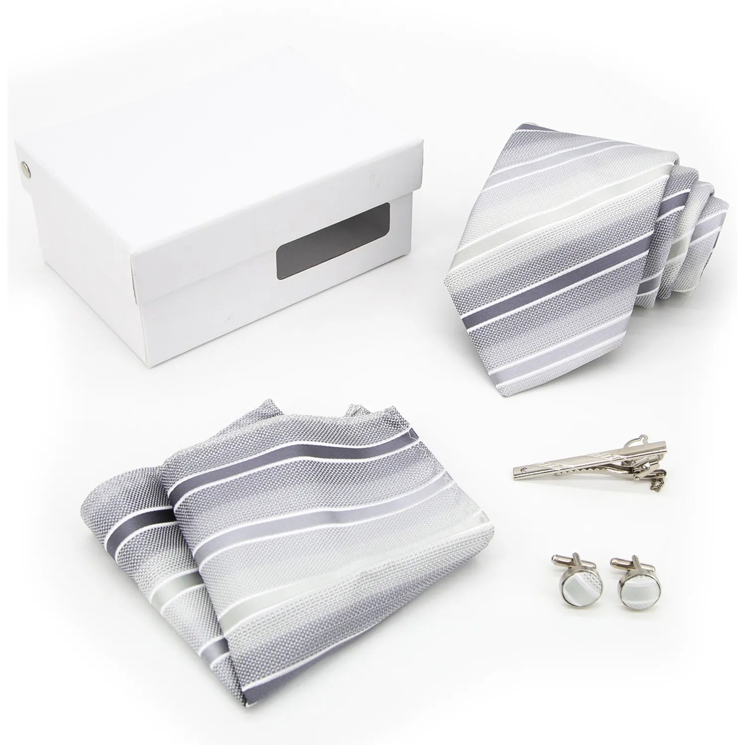 A complete men's tie gift box set, featuring a sophisticated silver-grey necktie with a refined pattern of dark grey and light geometric diamonds, a perfectly matched pocket square, and a pair of sleek silver-toned cufflinks, elegantly presented for a modern professional.