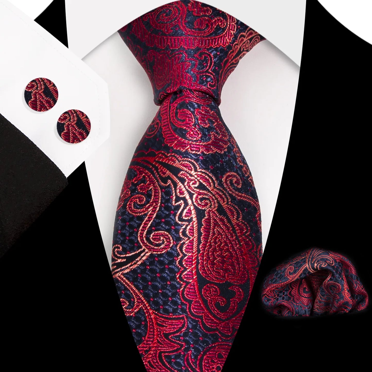Striking red and navy blue paisley patterned polyester tie, expertly knotted, with a matching pocket square and cufflinks, presented as a complete formal wear set.