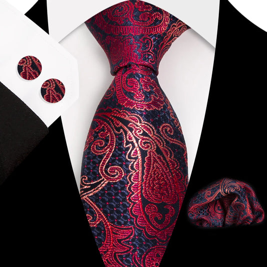Striking red and navy blue paisley patterned polyester tie, expertly knotted, with a matching pocket square and cufflinks, presented as a complete formal wear set.