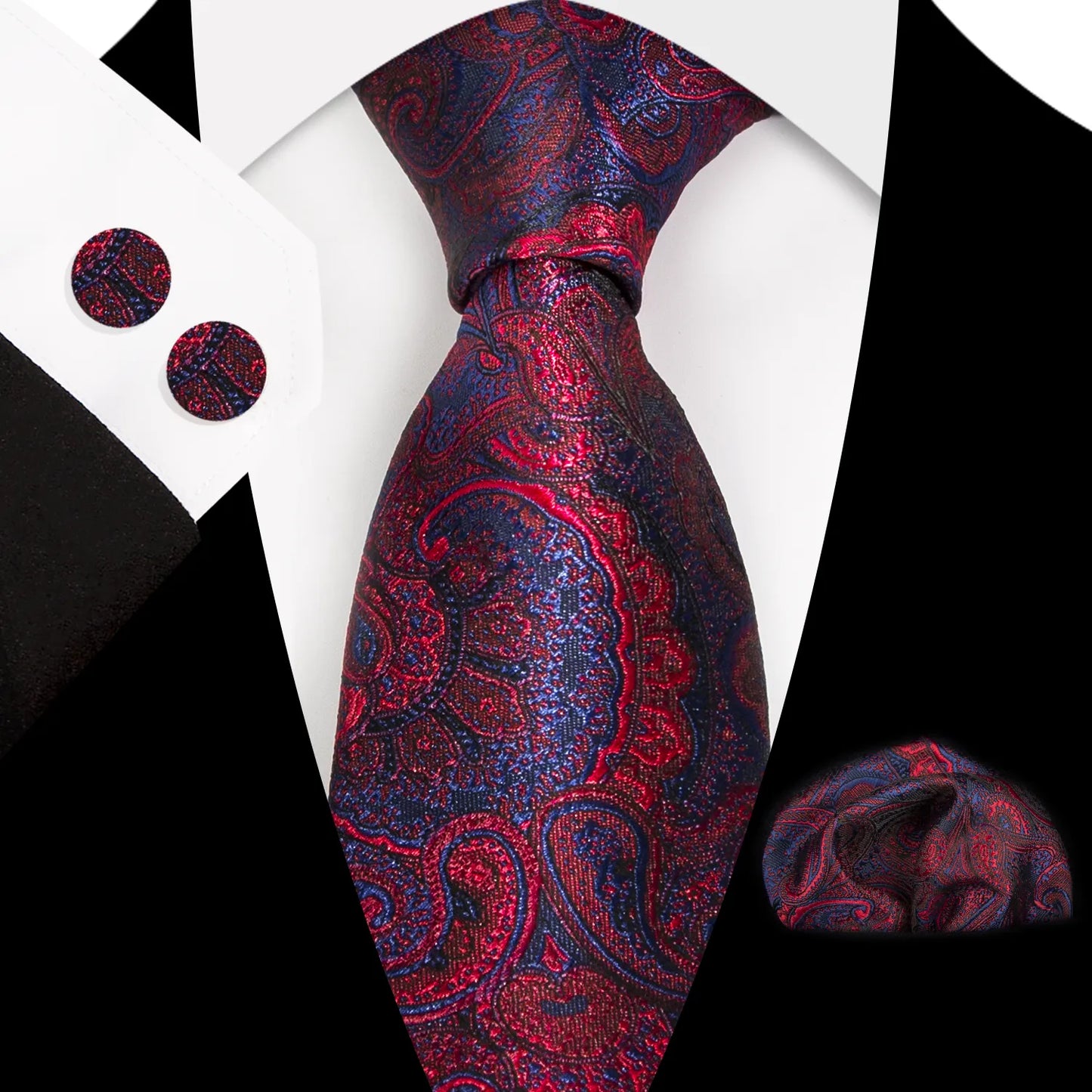 A close-up shot of a richly patterned polyester tie in a deep red and navy paisley design, worn with a white shirt and black suit, accompanied by a matching pocket square and cufflinks.